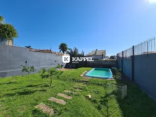 Foto externa mostrando uma piscina e um gramado verde em uma propriedade.