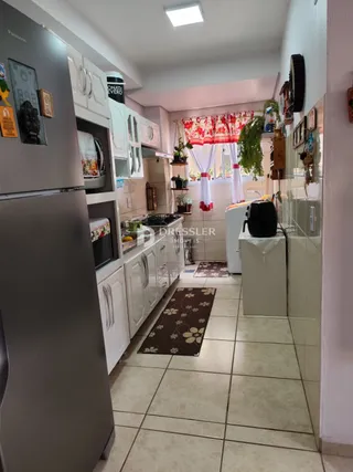Interior de uma cozinha com armários brancos e piso de cerâmica.
