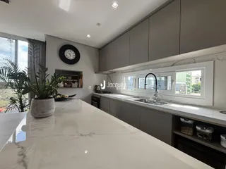 Vista da cozinha moderna com armários cinzas e bancadas brancas.