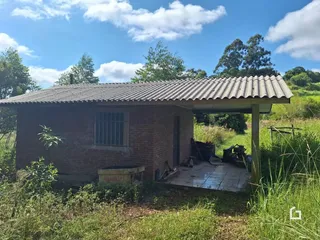 Fachada de uma casa de tijolos com telhado de metal na área rural.