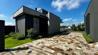 Foto da fachada de uma casa moderna com pátio pavimentado e jardim.