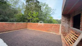 Área externa com muro de tijolos e piso de cascalho.