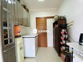 Foto interna de uma cozinha com armários e eletrodomésticos.