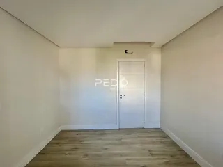 Hall de entrada com piso de madeira clara e porta branca.