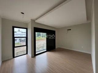 Interior de uma sala com piso de madeira e grandes janelas.