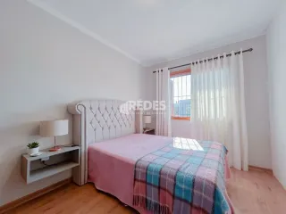 Quarto com cama e paredes brancas em uma residência.