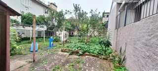 Vista externa de um quintal com vegetação e área de terra.