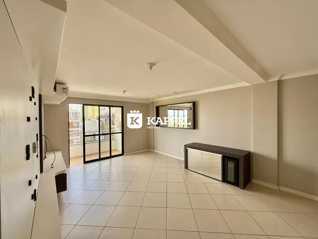 Uma sala de estar ampla com piso de cerâmica clara e portas de vidro que dão acesso ao exterior.