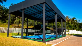 Vista externa de uma área coberta com gramado e cerca.