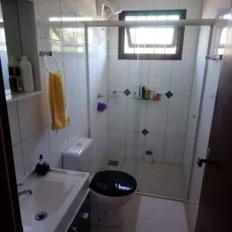 Foto interna de um banheiro com revestimento cerâmico branco.
