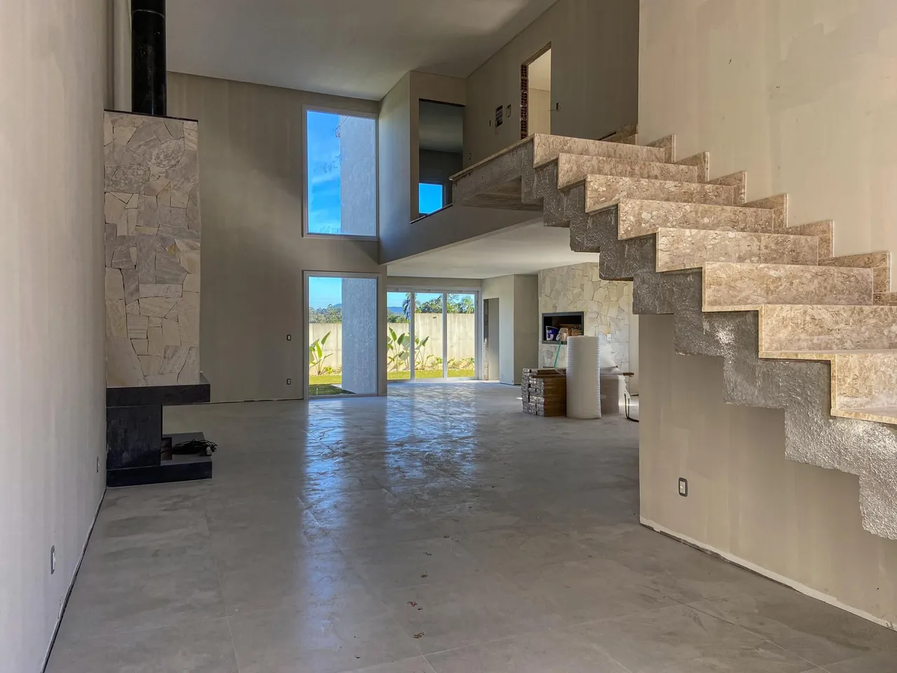 Vista ampla de um ambiente interno com escadaria e lareira em uma residência.