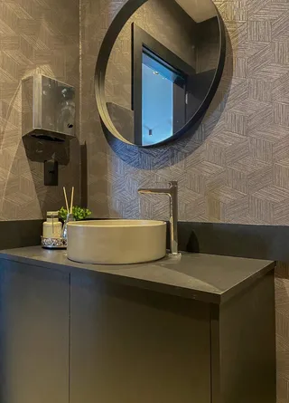 Foto de um banheiro moderno com bancada escura e revestimento de parede texturizado.