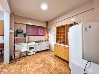 Interior da cozinha com armários de madeira e piso cerâmico.