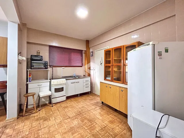 Interior da cozinha com armários de madeira e piso cerâmico.