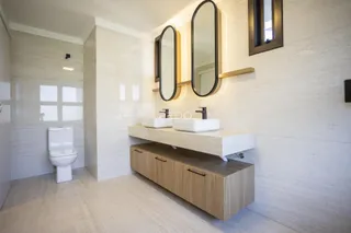 Banheiro moderno com revestimento branco e bancada de madeira clara.