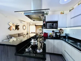 Foto de uma cozinha moderna com armários brancos e bancadas escuras.