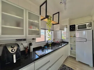 Vista da cozinha moderna com armários brancos e bancadas escuras.