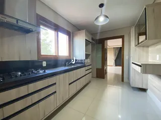 Vista da cozinha com armários de madeira e janela em um imóvel no Brasil.