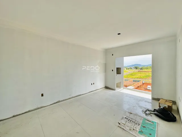 Sala ampla e vazia com piso de cerâmica e paredes brancas.