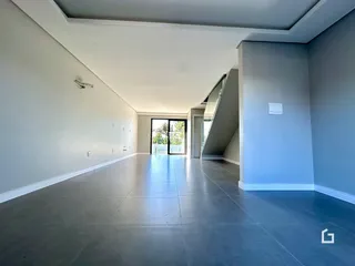 Espaço interno amplo com piso de concreto polido e paredes brancas.