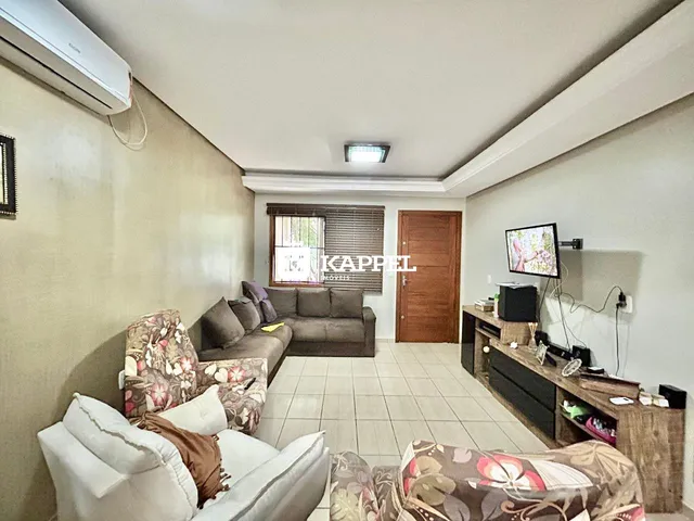 Sala de estar com sofás e televisão em um ambiente claro.