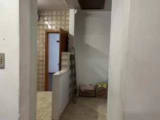 Hall de entrada com parede branca e piso de cerâmica visível no fundo.