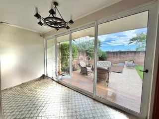 Vista interna de uma sala com portas de vidro que dão acesso a um pátio externo.