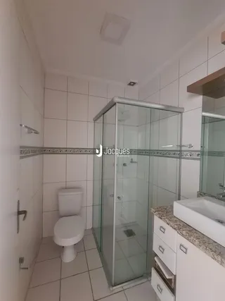Foto de um banheiro com box de vidro e piso cerâmico.
