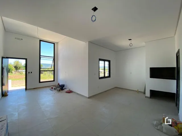 Ambiente interno de uma sala ampla com paredes brancas e piso claro.
