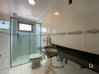 Foto de um banheiro com revestimento cerâmico e box de vidro.