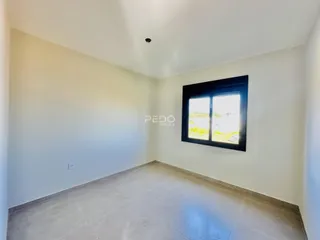 Vista interna de um ambiente com paredes brancas e piso claro.