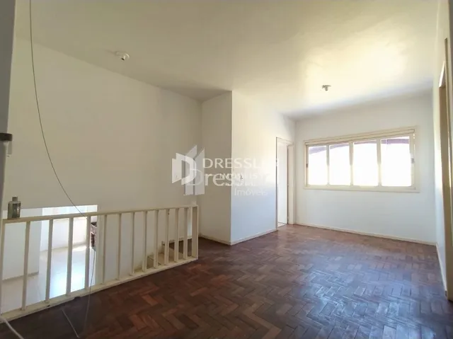 Interior de um ambiente com piso de madeira e paredes brancas.
