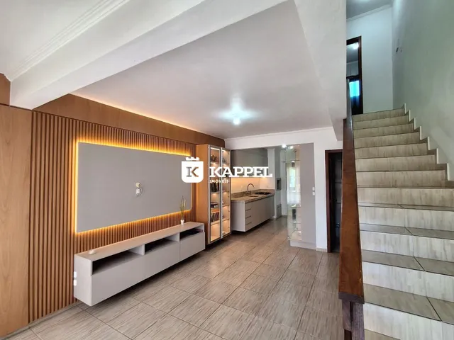 Vista interna de uma sala com painel decorativo e área de cozinha moderna.