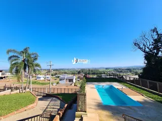 Foto da área externa com piscina e jardim de uma propriedade em Lajeado.