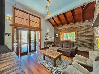 Sala de estar com piso de madeira e portas de vidro que dão acesso ao exterior.