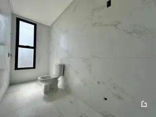Foto de um banheiro com revestimento em mármore branco e piso claro.