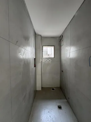 Corredor interno de uma residência com paredes brancas e piso claro.