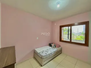 Quarto com cama e janela de madeira em um imóvel em Lajeado.
