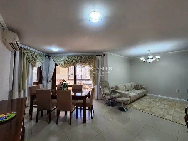 Sala de jantar com mesa de madeira e cortinas na residência.