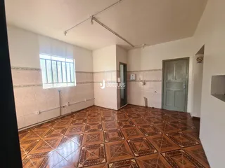 Interior de uma sala com piso de ladrilhos marrons e parede clara.