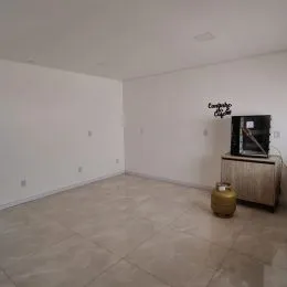 Foto de um ambiente interno amplo e vazio com paredes brancas e piso claro.