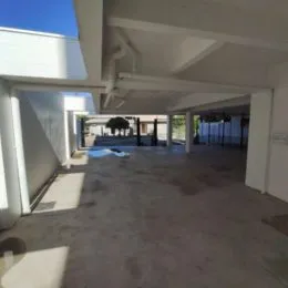 Vista interna de um espaço amplo com piso de concreto e estrutura de teto.