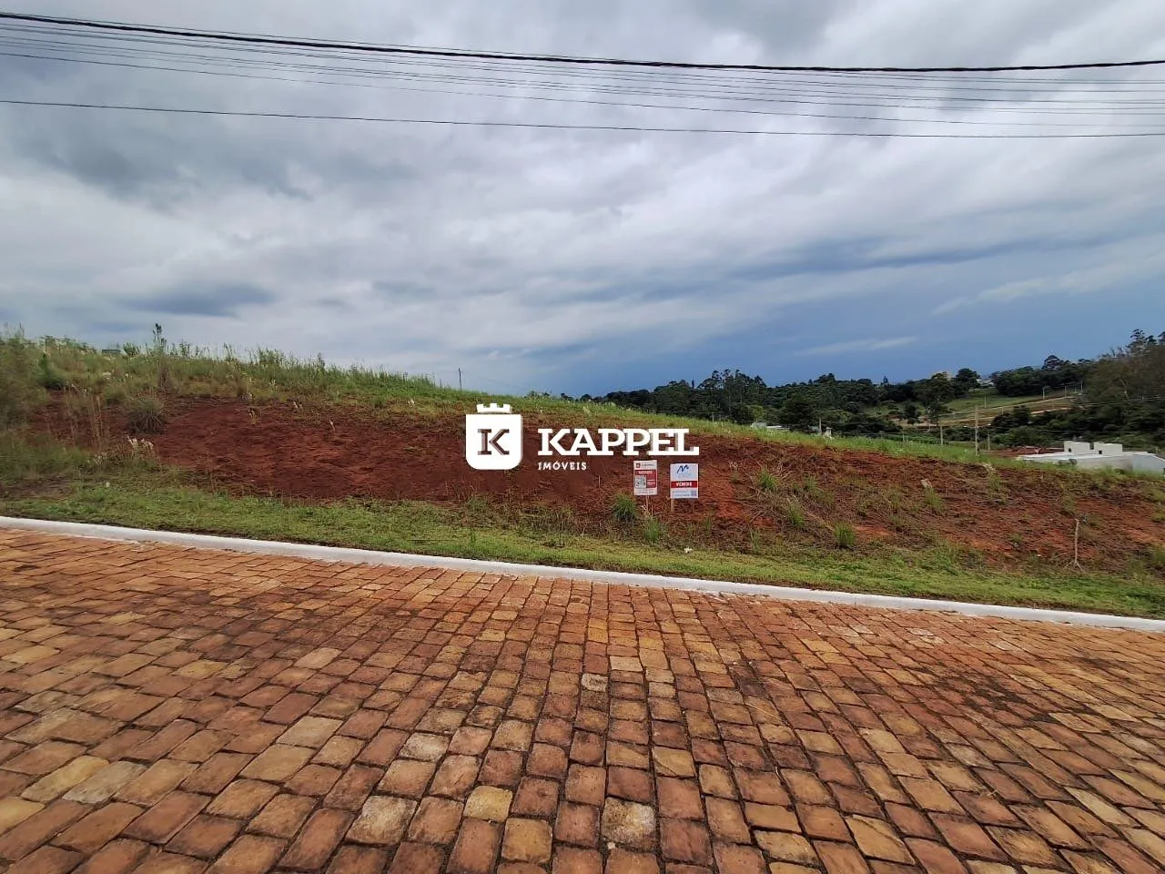 Vista externa de uma propriedade com um terreno inclinado e sinalização no fundo.
