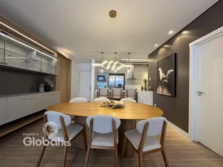 A sala de jantar apresenta uma mesa de madeira com cadeiras brancas em um ambiente moderno.