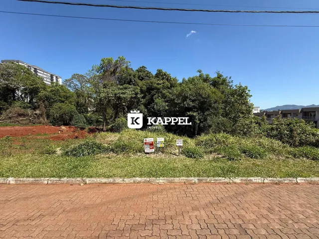 Foto externa mostrando uma área verde com vegetação e uma placa de imobiliária.