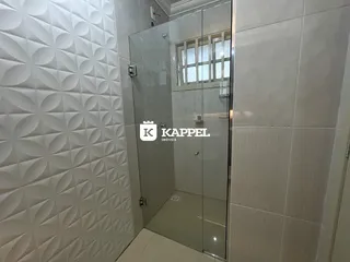 Banheiro com box de vidro e revestimento de cerâmica.