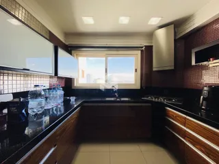 Foto da cozinha com armários de madeira e bancadas escuras.