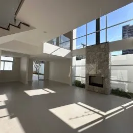 Ambiente interno amplo com piso claro e grandes janelas.