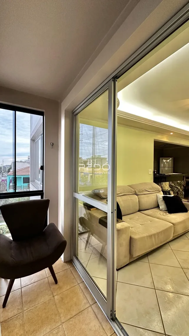 Vista de um ambiente interno com portas de vidro que se abrem para outra sala.