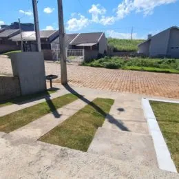 Vista externa mostrando uma área de concreto e grama.